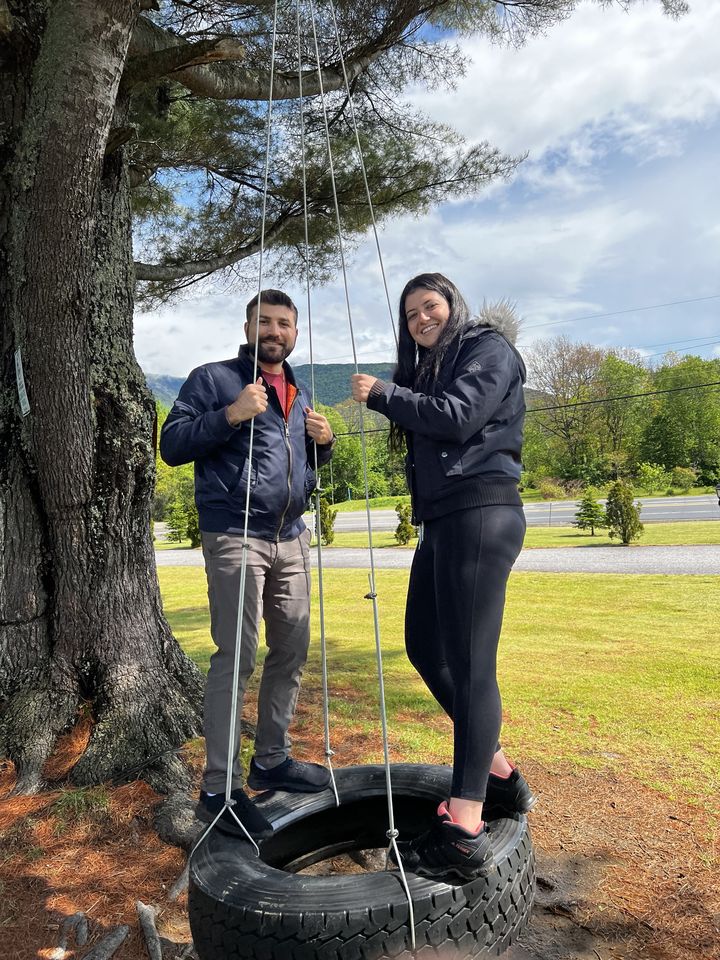 Jessica and Rami standing on a tire swing