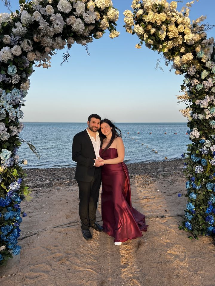 Jessica and Rami under a flower arch on the beach