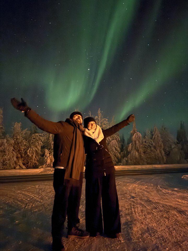 Jessica and Rami with arms outstretched under the northern lights