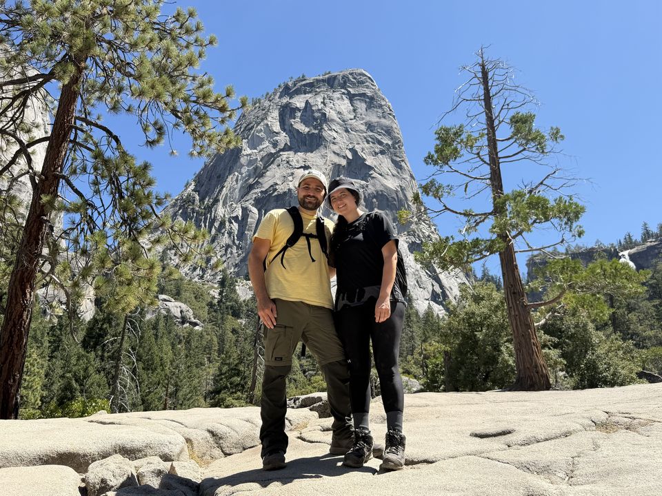 Jessica and Rami hiking beneath a granite dome among pine trees