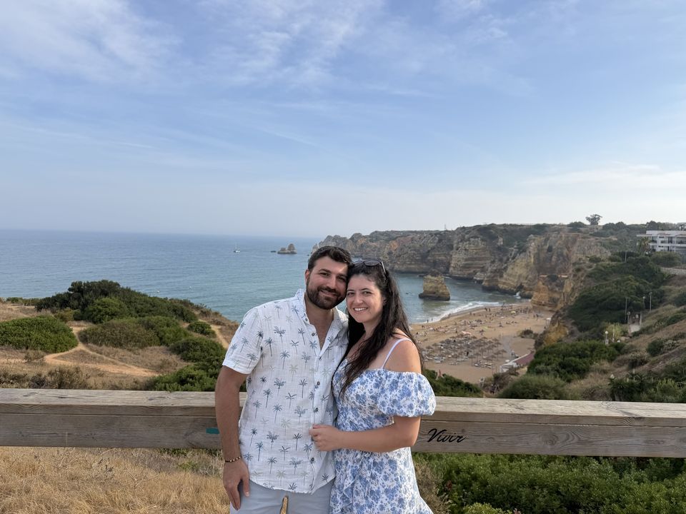 Jessica and Rami on a clifftop overlooking a beach and the sea